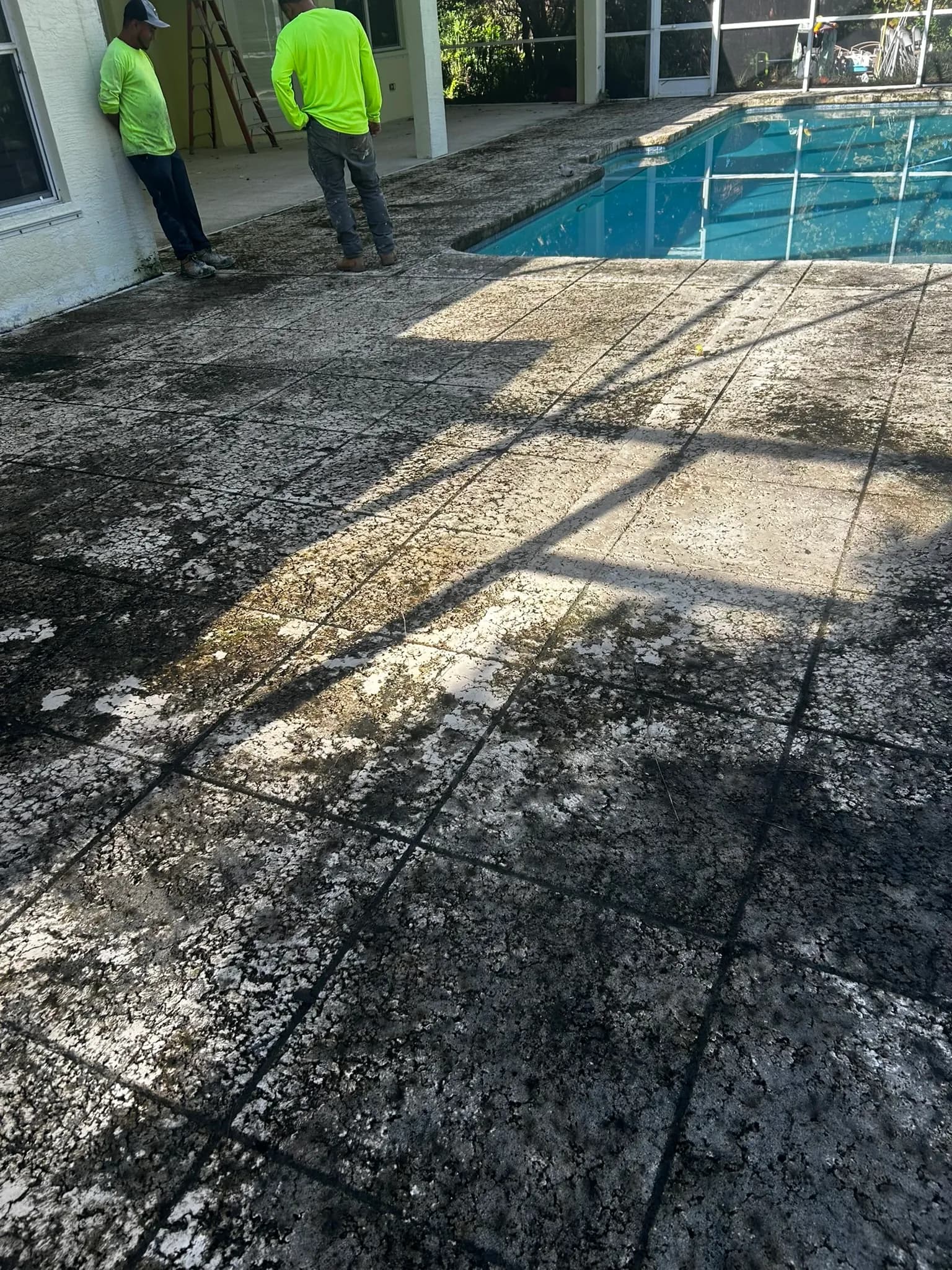 Deteriorated pool deck before resurfacing showing worn surface and staining